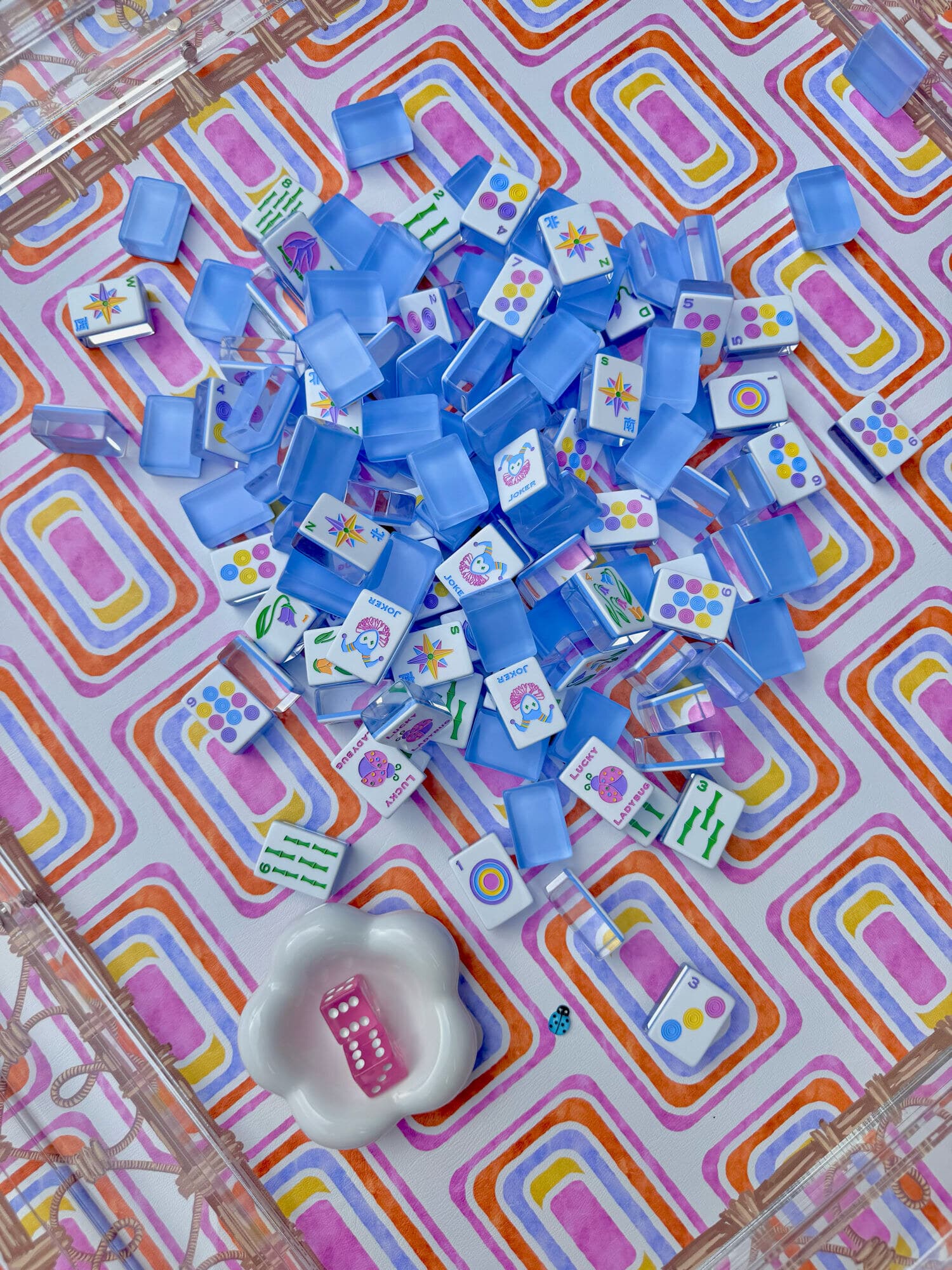 Cornflower blue mahjong tiles scattered on a pink and orange geometric mat